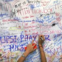 A woman writes a message of support for family members of missing passengers who were onboard Malaysia Airlines’ Flight 370, at Kuala Lumpur International Airport in Sepang, outside the Malaysian capital, in March 2014. Tech advances will one day lead to discovery of MH370's resting place, chief executive says