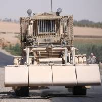 A U.S. military de-mining vehicle leads a convoy on the main road in Raqqa, Syria, on Monday. | REUTERS