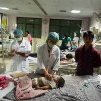 Medical staff attend to a child admitted in the encephalitis ward at the Baba Raghav Das Hospital in Gorakhpur, in the northern Indian state of Uttar Pradesh, on Saturday. At least 60 children have reportedly died recently at the government-run hospital. | AFP-JIJI