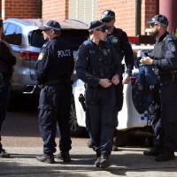 Police emerge from a block of flats in the Sydney suburb of Lakemba on Tuesday after counterterrorism raids across the city over the weekend. Four men accused of plotting to bring down a plane planned to use poisonous gas or a crude bomb disguised as a meat mincer, reports said on Sunday, with Australian officials calling preparations \"advanced.\" | AFP-JIJI