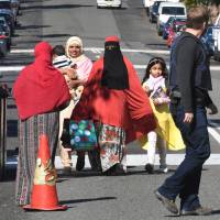 Police direct locals around a block of flats in the Sydney suburb of Lakemba on Tuesday after counterterrorism raids across the city over the weekend. | AFP-JIJI