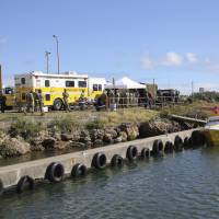 The Honolulu Fire Department Command Center is mobilized at a boat harbor Wednesday in Haleiwa, Hawaii. An Army helicopter with five on board crashed several miles off Oahu’s North Shore late Tuesday. Rescue crews are searching the waters early Wednesday. Search for five spots debris field off Oahu after Army Black Hawk goes down