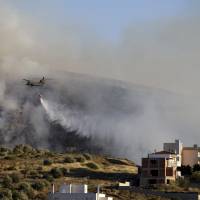 A helicopter drops water over a fire in the Kalyvia area some 30 km (18 miles) south of Athens, Monday. Dozens of firefighters, assisted by five water-dropping helicopter,s are battling a large brush fire south of Athens, but Greek authorities say no inhabited areas are in immediate danger. Greece battles big brush fire south of Athens