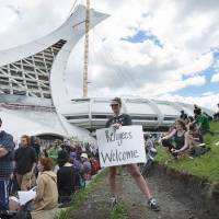 People hold up signs in support of asylum seekers during a rally outside the Olympic Stadium in Montreal Sunday. The stadium is now being used as a temporary shelter for some of the hundreds of asylum claimants pouring across the New York-Quebec border every day. Canada braces for surge in Haitian migrants facing loss of 'temporary protected status' in U.S.