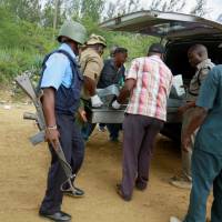 Kenyan policemen carry the bodies of a Swiss couple killed in Mombasa, Kenya, Sunday. Elderly Swiss couple found slain in Mombasa; caretaker missing
