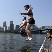 Residents of Portland, Oregon, leap into the Willamette River on Wednesday. | AP