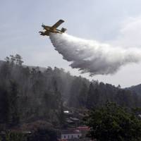 A firefighting plane drops its load to prevent wildfires from reigniting over the village of Agua Formosa, near Vila de Rei, central Portugal, Tuesday. 3,000 pressed into battle against raging Portugal wildfires