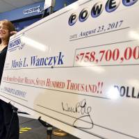 Mavis Wanczyk, of Chicopee, Massachusetts, stands by a poster of her winnings during a news conference where she claimed the $758.7 million Powerball prize at Massachusetts State Lottery headquarters, Thursday in Braintree. Officials said it is the largest single-ticket Powerball prize in U.S. history. At left is state Treasurer Deb Goldberg. Massachusetts hospital worker 'will not be coming back' to work after huge Powerball lottery win