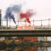 In this handout photo taken Sunday and released on Monday by Zona.media, Maria Alyokhina and Olga Borisova, members of the Russian punk band Pussy Riot, hold flares and a banner on the bridge outside the prison colony in Yakutsk, Russia, Monday. Film director Oleg Sentsov of Crimea, which Russia annexed from Ukraine in 2014, was convicted of conspiracy to commit terror attacks by a Russian military court in 2015 and sentenced to 20 years in prison. Pussy Riot pair held after protesting for Ukrainian filmmaker's release from Siberia prison