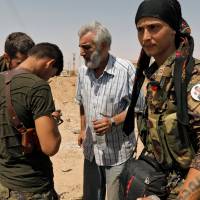 A man who fled Raqqa city talks to members of the Syrian Democratic Forces before being relocated, in Harqala, west of Raqqa, Syria, Tuesday. | REUTERS