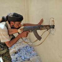 A member of the Syrian Democratic Forces keeps watch as his comrades try to lacate an Islamic State sniper in Al Senaa, a district of Raqqa, Syria, Thursday. Islamic State fighters trapped in Raqqa, but Chechen snipers slow U.S.-backed forces