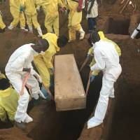 Volunteers handle a coffin during a mass funeral for victims of heavy flooding and mudslides in Regent at a cemetery in Freetown Aug. 17. More than 1,000 people have died from the mudslide and flood that hit Sierra Leone’s capital nearly two weeks ago, Sunday, according to a local leader and a minister during services honoring the disaster’s victims. Sierra Leone mudslide death toll now over 1,000 but actual number killed may never be known
