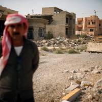 A Yazidi man stands in front of destroyed houses in Sinjar region, Iraq, Wednesday. | REUTERS