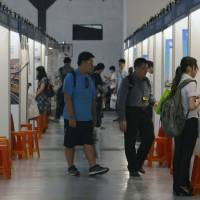 Visitors walk past recruitment booths during a job fair in Taipei on July 1. Despite political rivalries, brain drain feared as young Taiwanese choose to work in China