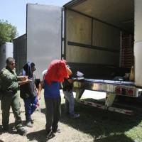 Border Patrol officers escort a group of immigrants to a van Sunday after a group was found in the tractor-trailer in Edinburg, Texas. Police in Texas acting on a tip found the immigrants locked inside the tractor-trailer parked at a gas station about 20 miles from the border with Mexico, less than a month after 10 people died in the back of a hot truck with little ventilation in San Antonio. Tip leads police to 17 immigrants locked inside big rig at Texas truck stop