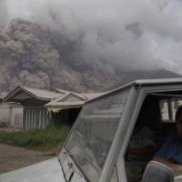 Residents ride in a truck as Mount Sinabung releases pyroclastic flows during its eruption in Karo, North Sumatra, Indonesia, Wednesday. The volcano blasted volcanic ash as high as 4.2 km, one of its biggest eruptions in the past several months of high activity. | AP