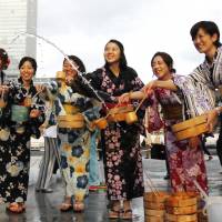 Women participate in \'uchimizu,\' a Japanese water-throwing tradition at a summer festival in Tokyo on Friday. On the same day, new Justice Minister Yoko Kamikawa said the ministry is considering submitting a bill to lower Japan\'s legal age of adulthood from 20 to 18. | AP