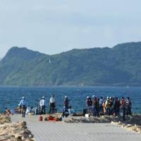 Police officers search a beach in Koga, Fukuoka Prefecture, on Friday following a drowning accident. | KYODO