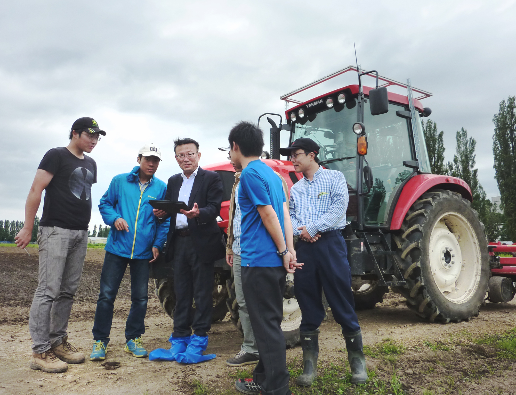 Hokkaido University professor Noboru Noguchi (center) oversees a test on a tractor operated with a tablet computer on the university campus in Sapporo on June 27. | KYODO