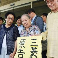 Kim Jae-rim (center), one of the South Koreans suing Mitsubishi Heavy Industries, holds up a sign announcing victory on Friday after the Gwangju District Court ordered the heavy machinery maker to pay Kim and three other victims of forced labor during the war 470 million won in compensation. | KYODO