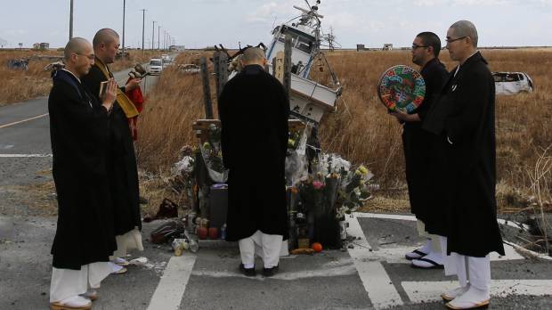 Buddhist monks offer prayers for victims of the March 11, 2011, earthquake and tsunami in Namie, Fukushima Prefecture, in March 2014. No-go zones keep kin from burying deceased Fukushima evacuees at ancestral gravesites