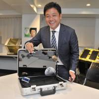 Nobu Okada, CEO of Astroscale PTE Ltd., shows off a miniature model of a “debris rotator” he developed, at the company’s Tokyo office on Aug. 2. Okada used to carry the gadget around to business meetings to promote his space junk removal project. Astroscale exec to boldly clean where no one has cleaned before