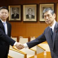 Song Tao (left), head of the international department of the Communist Party of China, shakes hands with Liberal Democratic Party Vice President Masahiko Komura at LDP headquarters in Tokyo on Monday. | KYODO