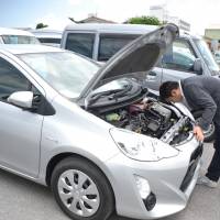 An exporter checks a used vehicle at a facility set up by Orix Auto Corp. in Tomigusuku, Okinawa Prefecture, on Aug. 1. Okinawa positions itself as hub for used rental-car exports