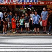 People stand in front of a crosswalk in Tokyo’s Akihabara district on Tuesday. A mere 51 hospitals — just 3 percent of those surveyed — had in-house medical coordinators to guide non-Japanese patients. Japan's medical support system falls short amid influx of foreign tourists, residents