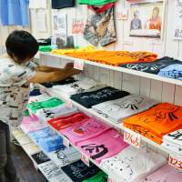 Keiko Sasaki arranges a display of T-shirts at her boutique Parisien in Tokyo’s Harajuku district on July 26. From subculture chic to mainstream style trend: Japanese-themed T-shirts are all the rage