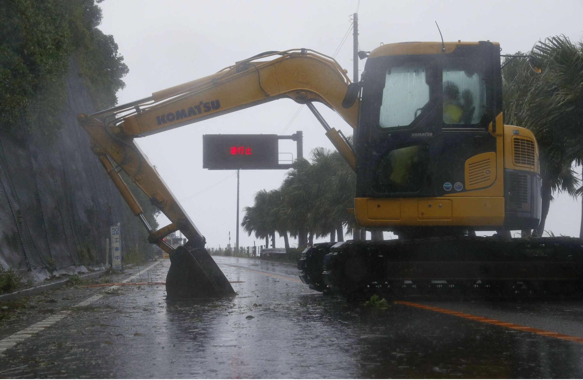 A digger is parked across a national highway in Nichinan, Miyazaki Prefecture, on Sunday to block access to it after the road was closed due to Typhoon Noru. | KYODO