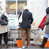 Left: People pack food distributed by Second Harvest Japan in bags before carrying them home. | NATSUKI YASUDA / STUDIO AFTERMODE
