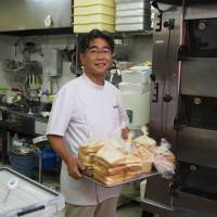 Tatsuya Sakamaki holds a tray of bread crusts at his bakery in Kawaguchi, Saitama Prefecture, in July. Even discarded crusts can go a long way in feeding the needy
