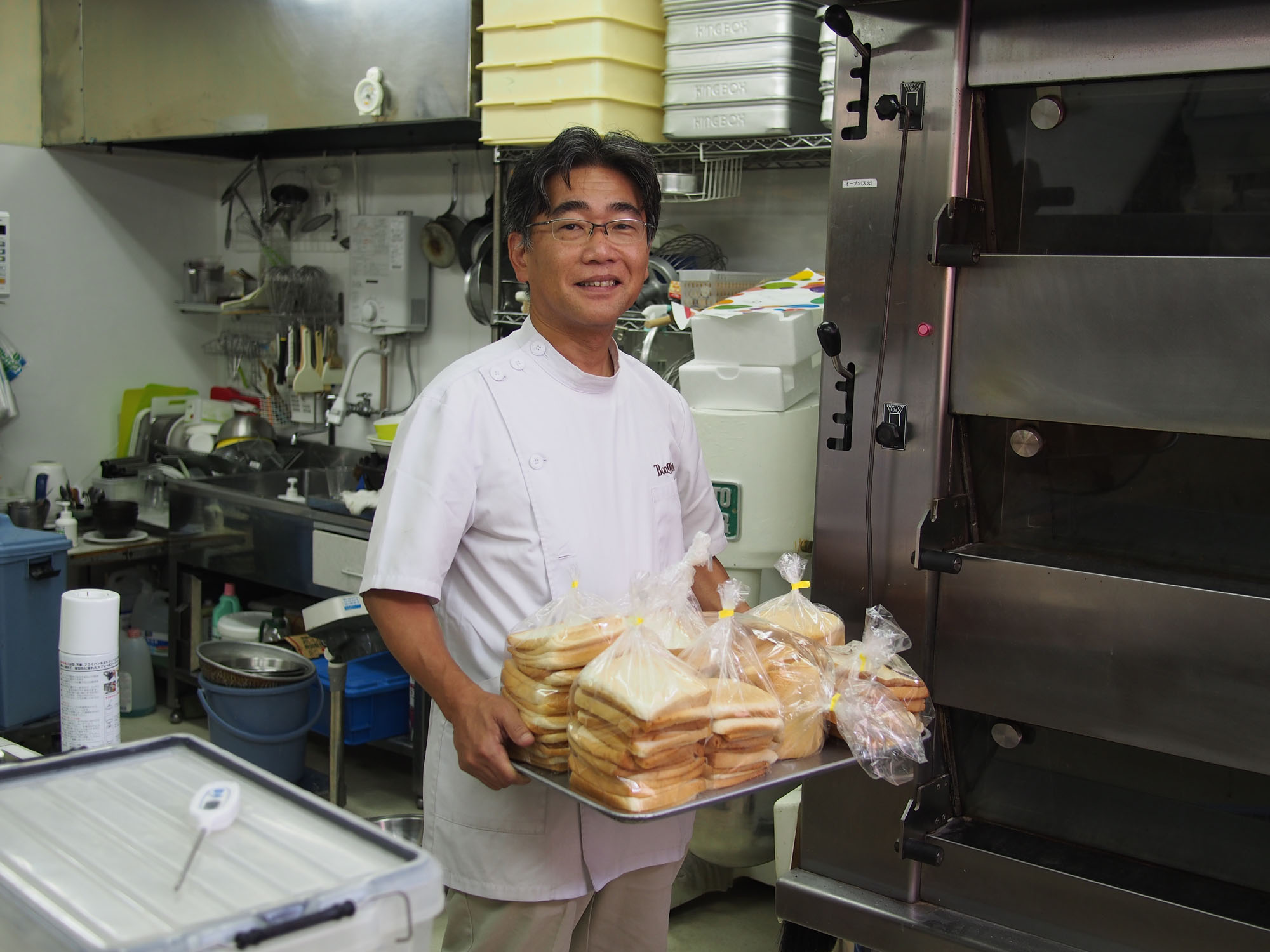 Tatsuya Sakamaki holds a tray of bread crusts at his bakery in Kawaguchi, Saitama Prefecture, in July. | MASAMI ITO