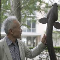 Professor Katsumi Tsukamoto poses beside an eel statue on the Shonan campus of Nihon University. Research breeds new hope for Japan's endangered eels