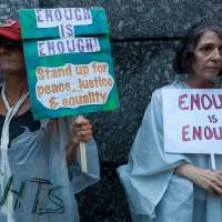 Time to take a stand: Organizers Sarajean Rossitto (left) and Jenise Treuting hold placards at the “Enough is Enough” rally near the U.S. Embassy in Toranomon, Tokyo, on Aug. 15, days after hate groups clashed violently with anti-fascist counterprotesters in Charlottesville, Virginia. Trump or decency? Every American, whether in Japan or elsewhere, must choose a side