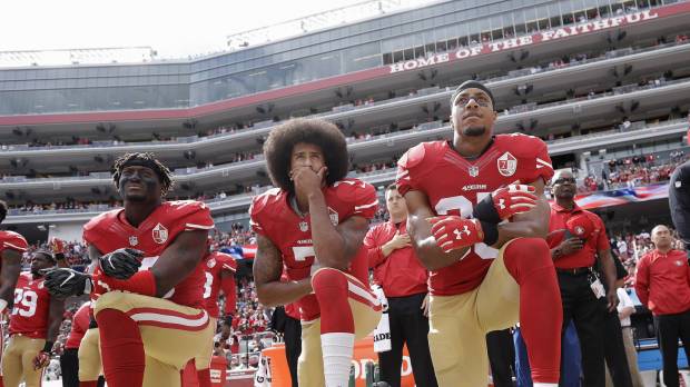 San Francisco players (from left) Eli Harold, Colin Kaepernick, and Eric Reed kneel during the national anthem on Oct. 2, 2016, in San Francisco. U.S. still in turmoil one year after Kaepernick's protest