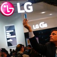 An attendee takes a photo on the LG Electronics Inc. stand on the opening day of the Mobile World Congress in Barcelona, Spain, in February. Apple, LG said to negotiate major OLED deal for iPhones starting 2019