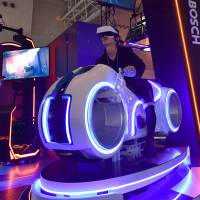 A visitor tries out a virtual reality motorcycle attraction reminiscent of “Tron” at a preview of the Tokyo Game Show on Thursday ahead of its official opening to the public this weekend. The attraction is the creation of Tokyo-based firm JPPVR technology. VR attractions to take center stage at Tokyo Game Show