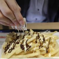 A man pours the toppings on a serving of McChoco Potato at a McDonald’s outlet in Tokyo. McDonald's secret sauce for success in Japan