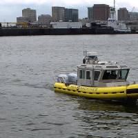 In this Aug. 15 photo, a boat capable of autonomous navigation makes its way around Boston Harbor. The experimental workboat spent this summer dodging tall ships and tankers, outfitted with sensors and self-navigating software and emblazoned with the words “UNMANNED VESSEL” across its aluminum hull. Long in the works, self-driving boats may make a splash before autonomous cars