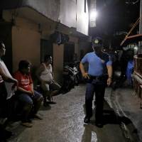 Residents of Caloocan watch policemen on patrol on Thursday. Entire Philippine city police sacked over killings and robbery