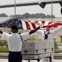 U.S. military personnel drape the national flag over a coffin containing possible remains of a U.S. serviceman during a repatriation ceremony at Phnom Penh International Airport on April 2, 2014. Cambodia suspends U.S. MIA searches, retaliating for visa ban
