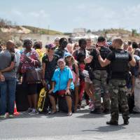 People wait at the Grand-Case Esperance airport to register to be evacuated Monday on the French Caribbean island of Saint-Martin, which was hit by Hurricane Irma. Military planes evacuate hurricane-hit tourists to Europe amid criticism of poor preparations