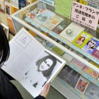 A woman looks at a book in front of a corner of donated Anne Frank-related material at a public library in Suginami Ward, Tokyo, in March 2014. New York exhibit allows virtual 'interviews' with Holocaust survivors