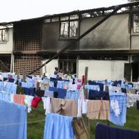 Parents observe the burned dormitory in front of the students’ laundry hanging on washing lines, following a fire at the Moi Girls High School in Nairobi on Saturday. Nine girls died early Saturday when a fire gutted their dormitory at the high school in Kenya’s capital, the country’s education minister said. Arson blamed for Kenya girls school inferno deadly to nine, seen as part of a trend