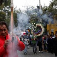 A man lights a firework as relatives carry the coffin of Maria Ortiz, who was a victim of the earthquake, during her burial in Mexico City Sunday. Hopes fade of finding more Mexico City quake survivors as search narrows down to two sites