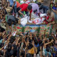 Rohingya Muslims who traveled from Myanmar into Bangladesh stretch their arms out to collect food items distributed by aid agencies near Balukhali refugee camp in Bangladesh on Monday. Amnesty International says fires continue at Rohingya villages in Myanmar