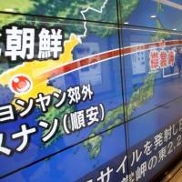 Passersby are reflected in a TV screen in Tokyo reporting news about North Korea’s missile launch on Sept. 15. North Korean H-bomb threat could see risky overflight of Japan by nuclear-tipped missile