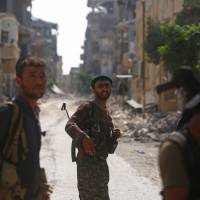 Members of the Syrian Democratic Forces walk in the former Islamic State stronghold of Raqqa on Thursday. Syrian fighters backed by U.S. special forces are battling to clear the last remaining Islamic State jihadis holed up in their crumbling stronghold. Islamic State fighters using human shields in Raqqa pockets as U.S.-backed forces take most of city